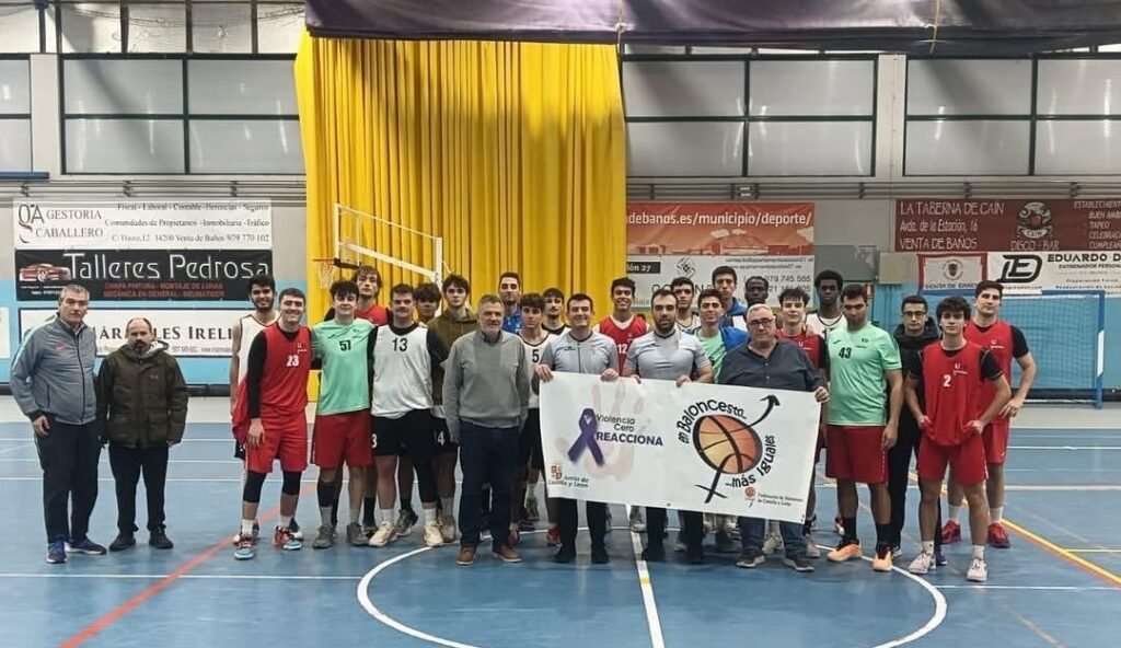 Group photo of male basketball players and coaches in an indoor court, holding a banner about anti-violence and basketball inclusion.A0