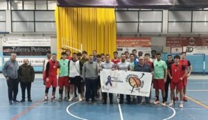 Group photo of male basketball players and coaches in an indoor court, holding a banner about anti-violence and basketball inclusion.A0