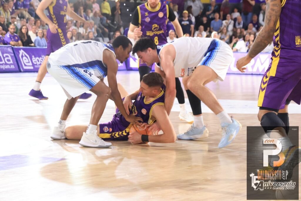 Basketball player in purple on the floor securing the ball while two opponents in white reach in.